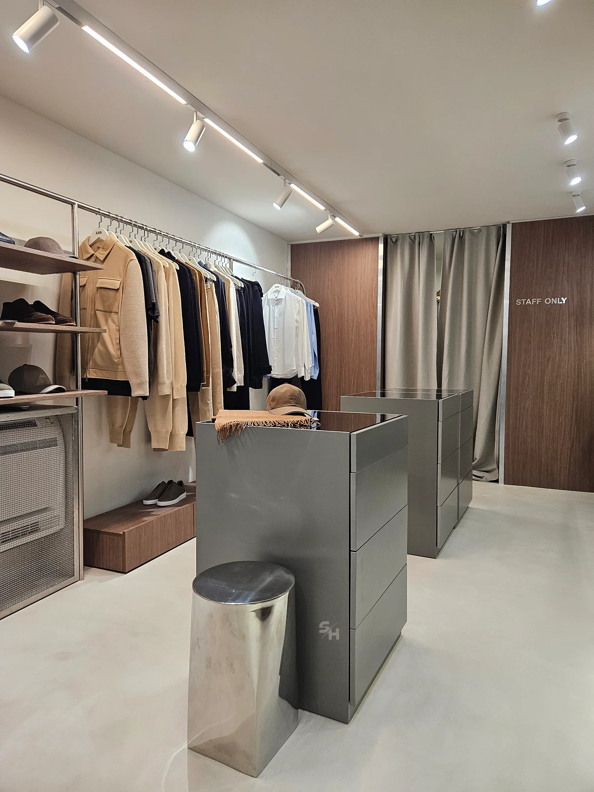 AND menswear store — sales floor with walnut-look wall units, clothing rails and display plinths