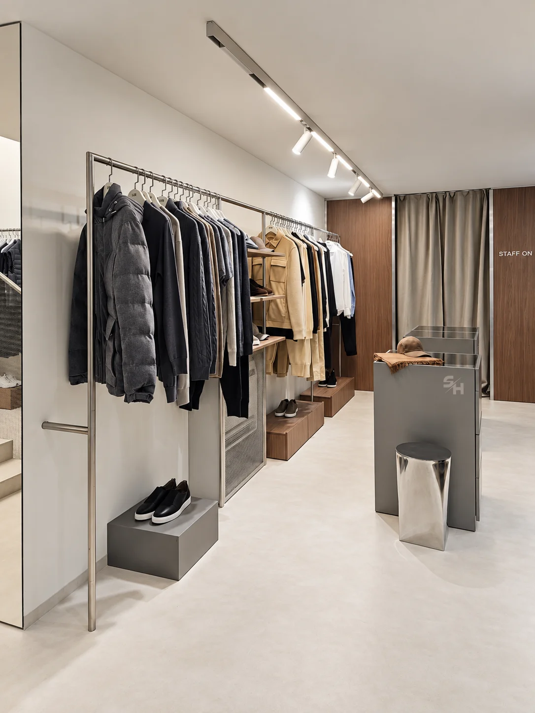 AND menswear store — sales floor with walnut-look wall units, clothing rails and display plinths