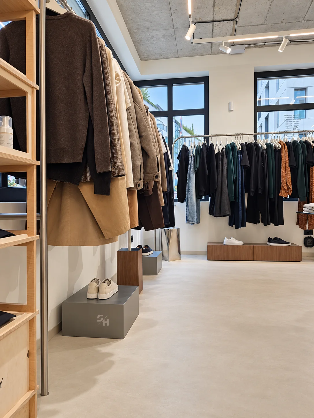 AND menswear store — sales floor with walnut-look wall units, clothing rails and display plinths