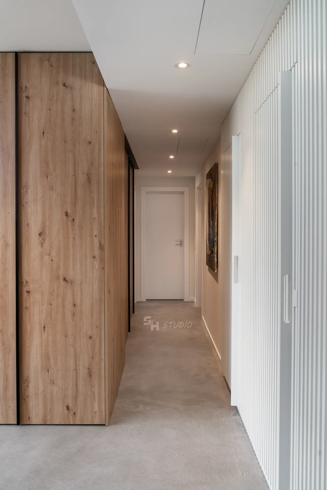 PHOBIA — entrance corridor with full-height timber storage and white fluted wall panelling