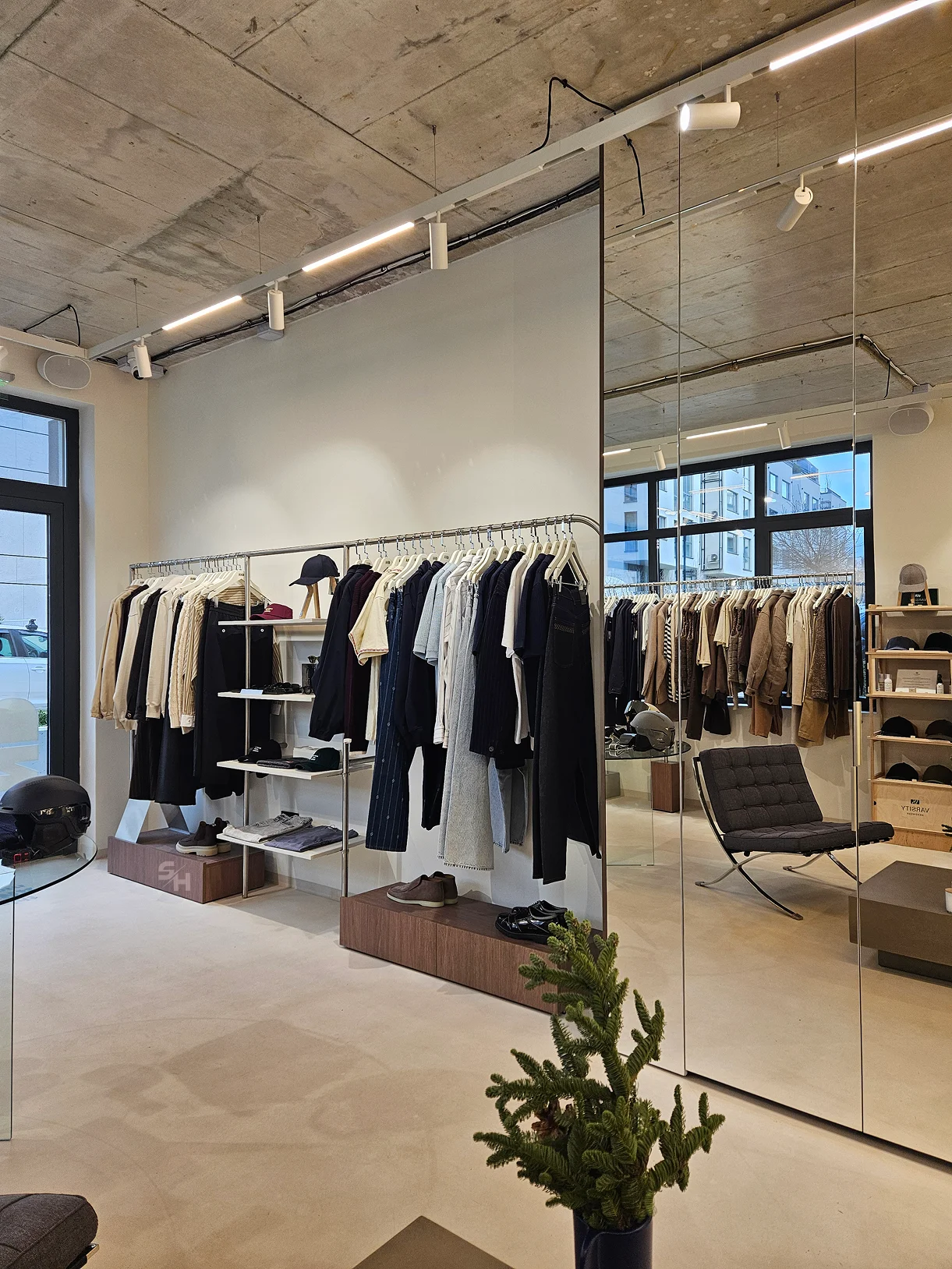 AND menswear store — sales floor with walnut-look wall units, clothing rails and display plinths