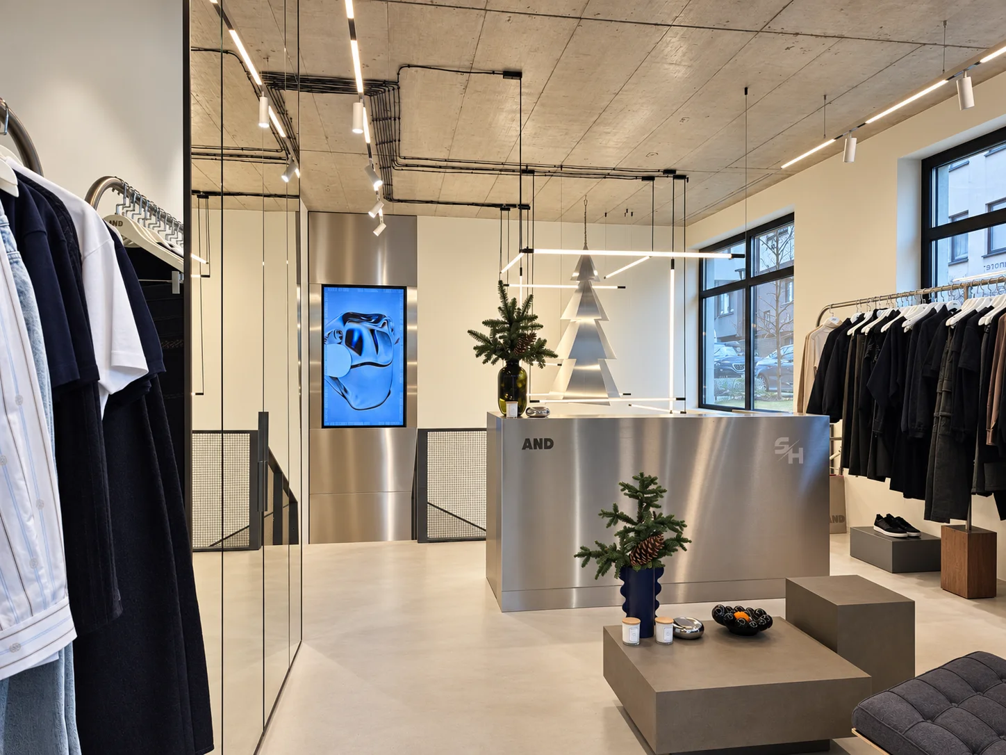 AND menswear store — sales floor with walnut-look wall units, clothing rails and display plinths