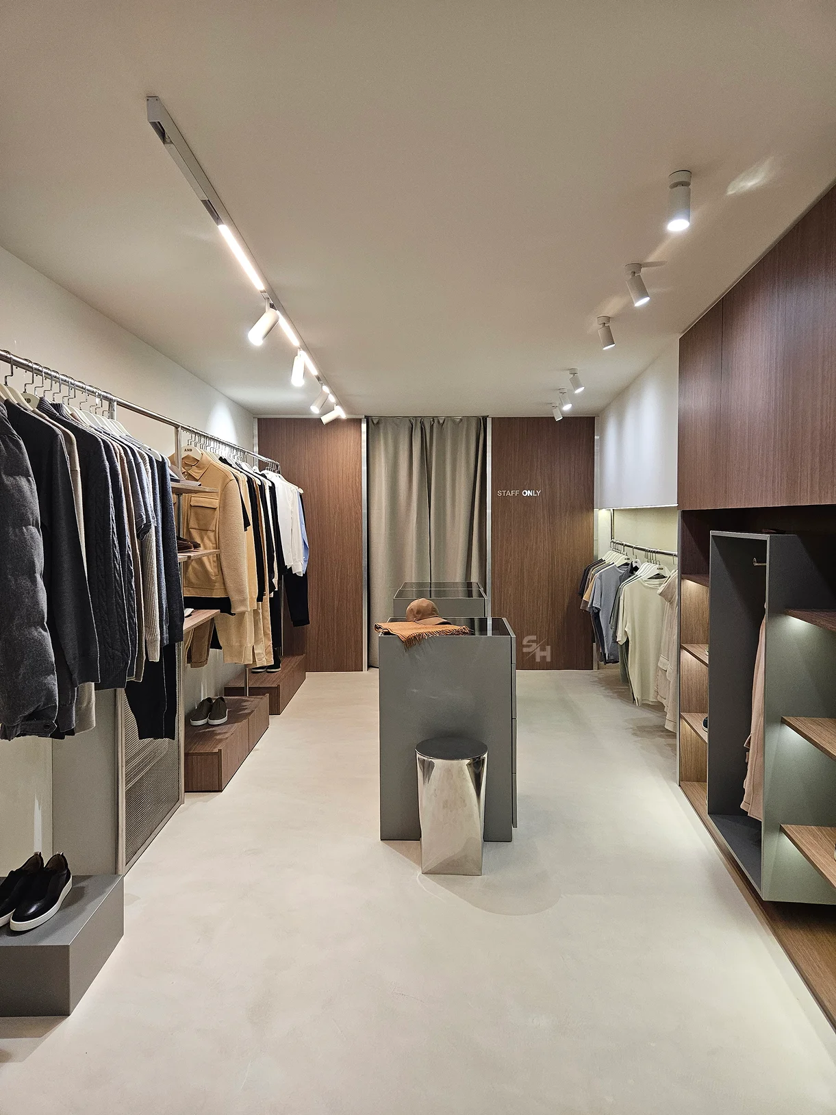 AND menswear store — sales floor with walnut-look wall units, clothing rails and display plinths