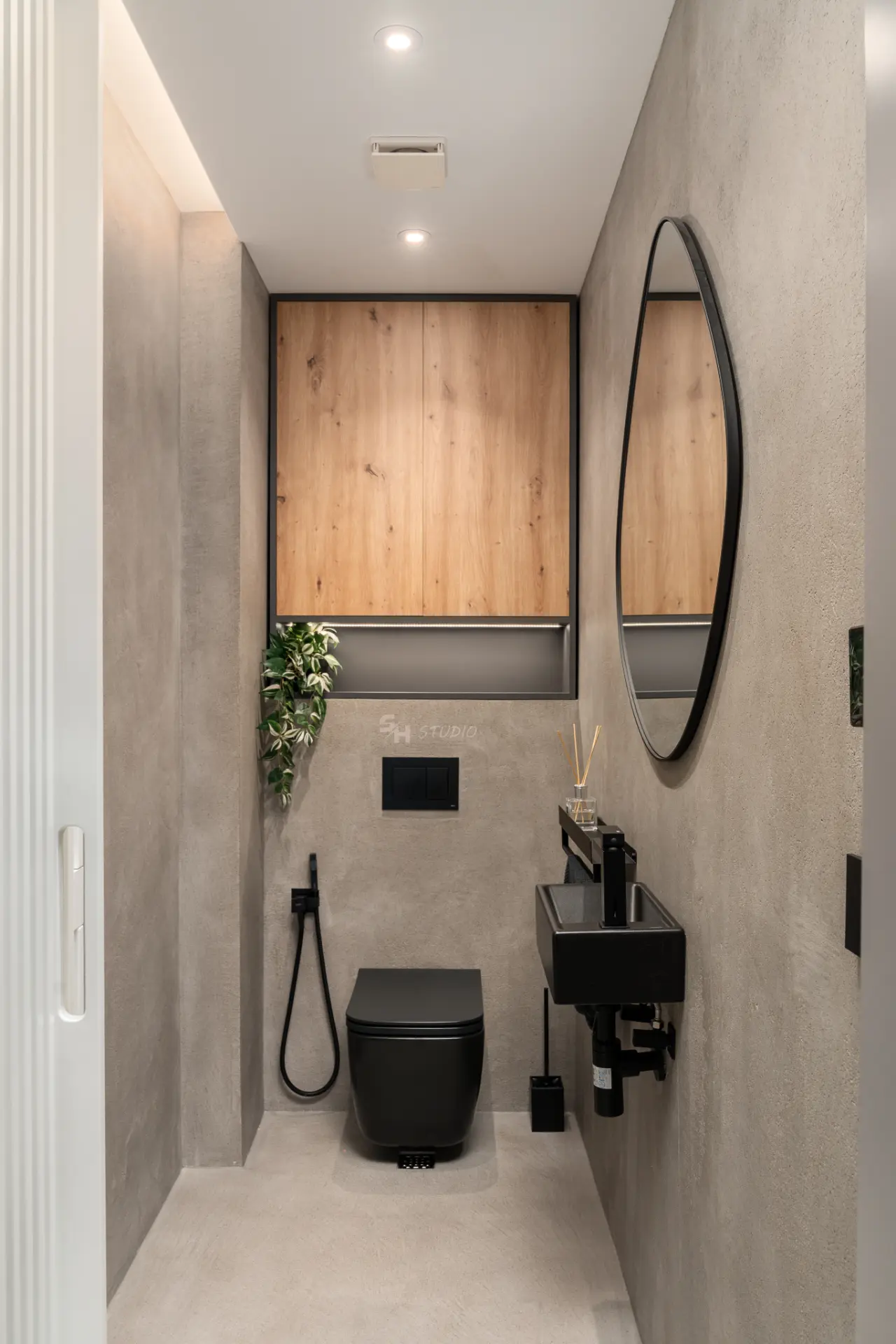PHOBIA — compact bathroom with wall-mounted basin, black fittings and integrated timber storage