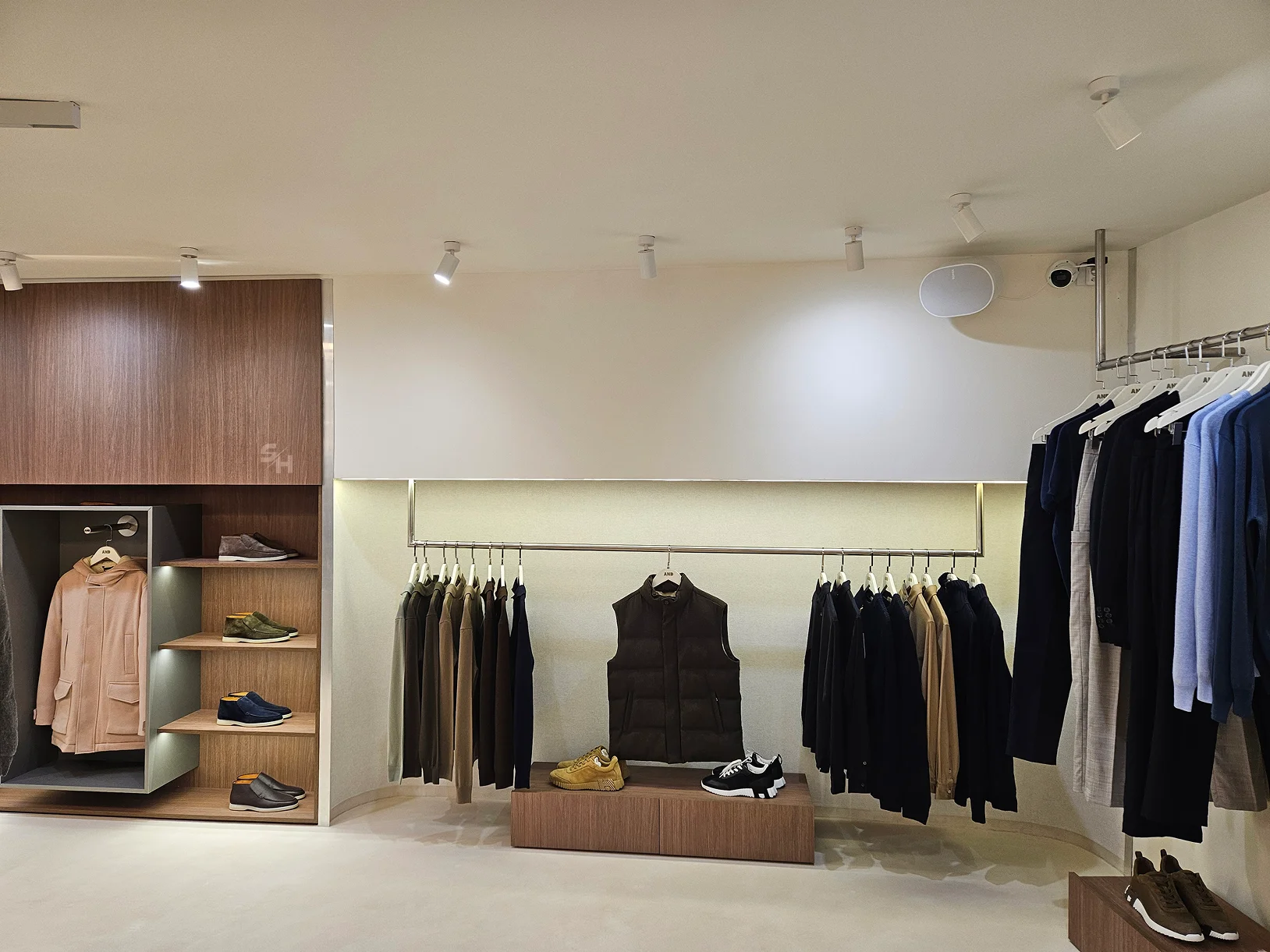 AND menswear store — sales floor with walnut-look wall units, clothing rails and display plinths