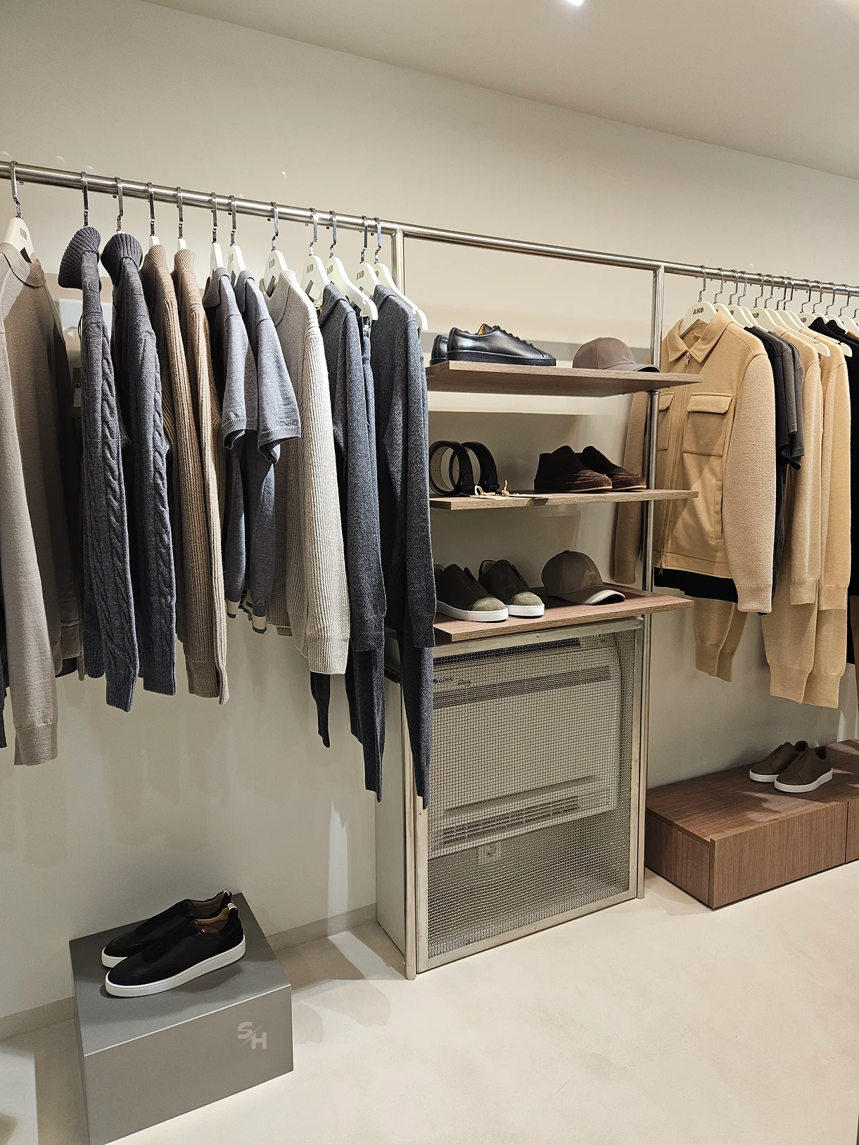 AND menswear store — sales floor with walnut-look wall units, clothing rails and display plinths